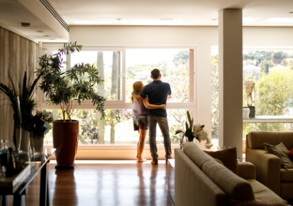 A couple standing and looking through a large window.
